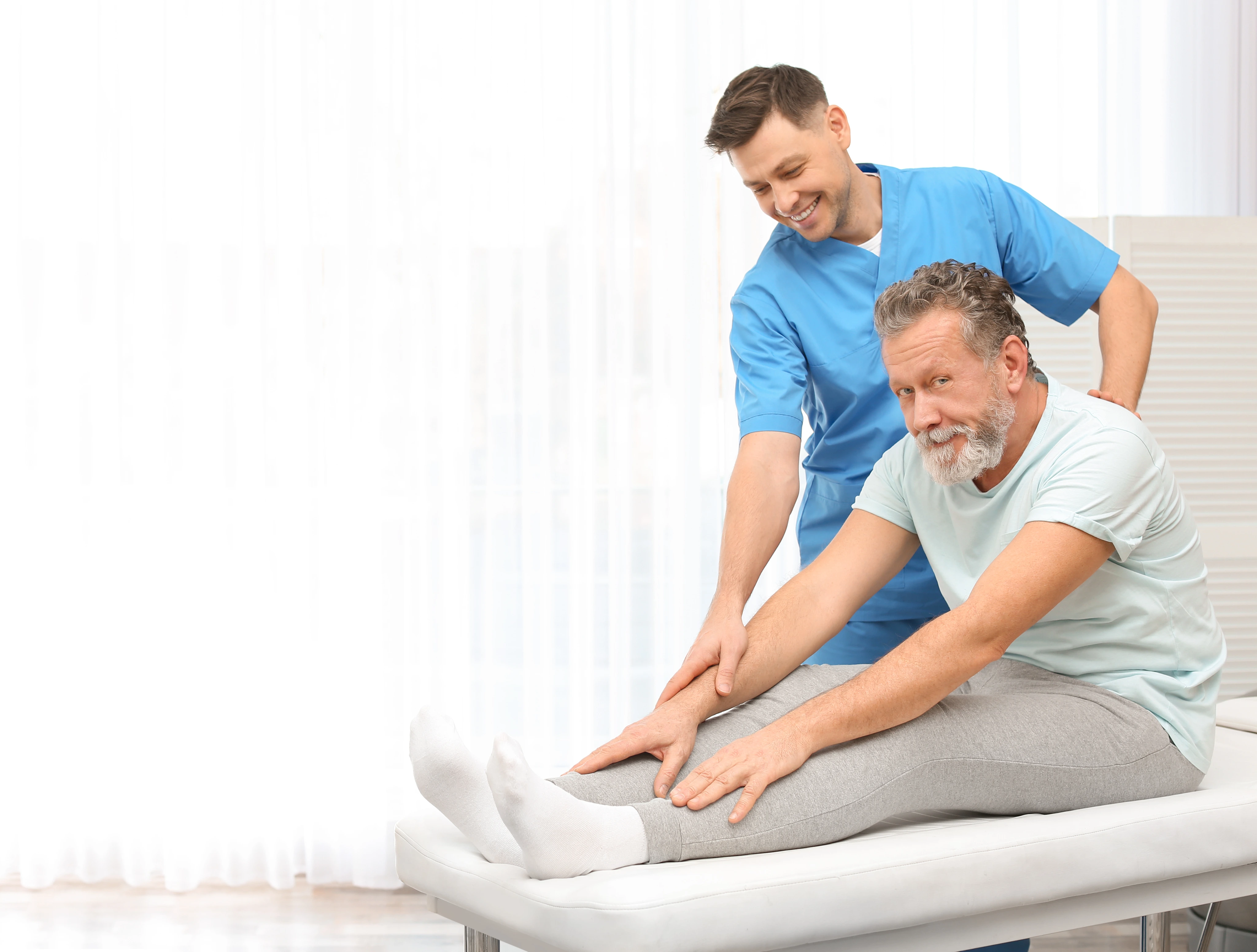 A chiropractor easing a patient through a seated stretch